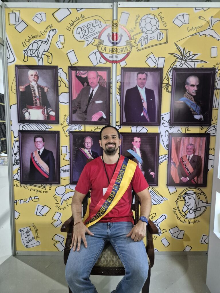 Johnny Manrique con banda presidencial frente a la galería de presidentes de La Historia con Wifi